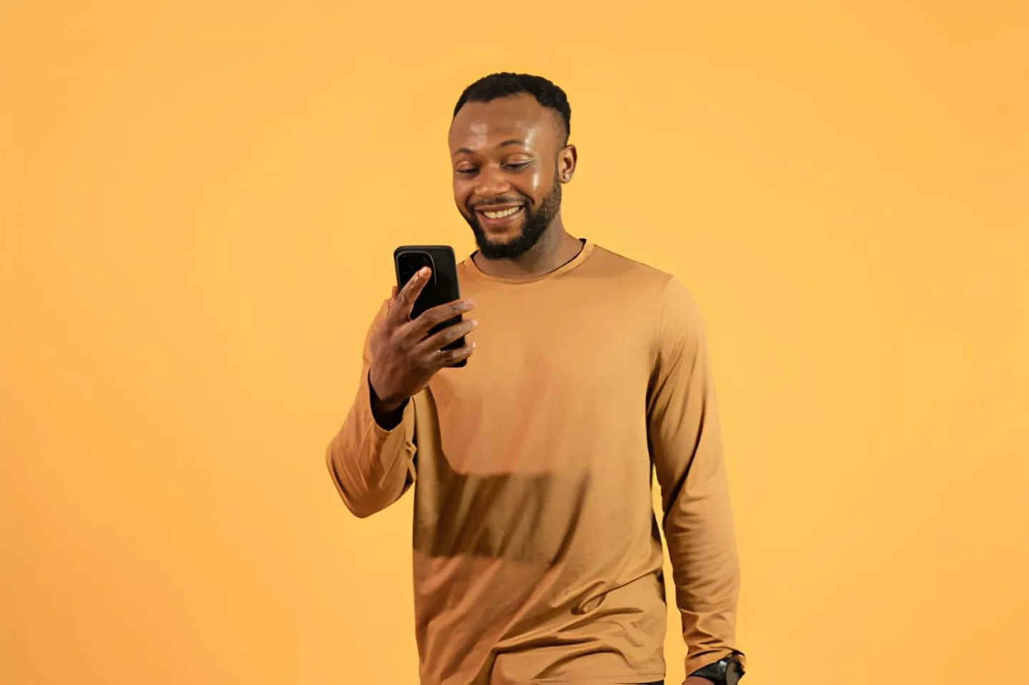 Smiling man looking at his phone checking his video performance