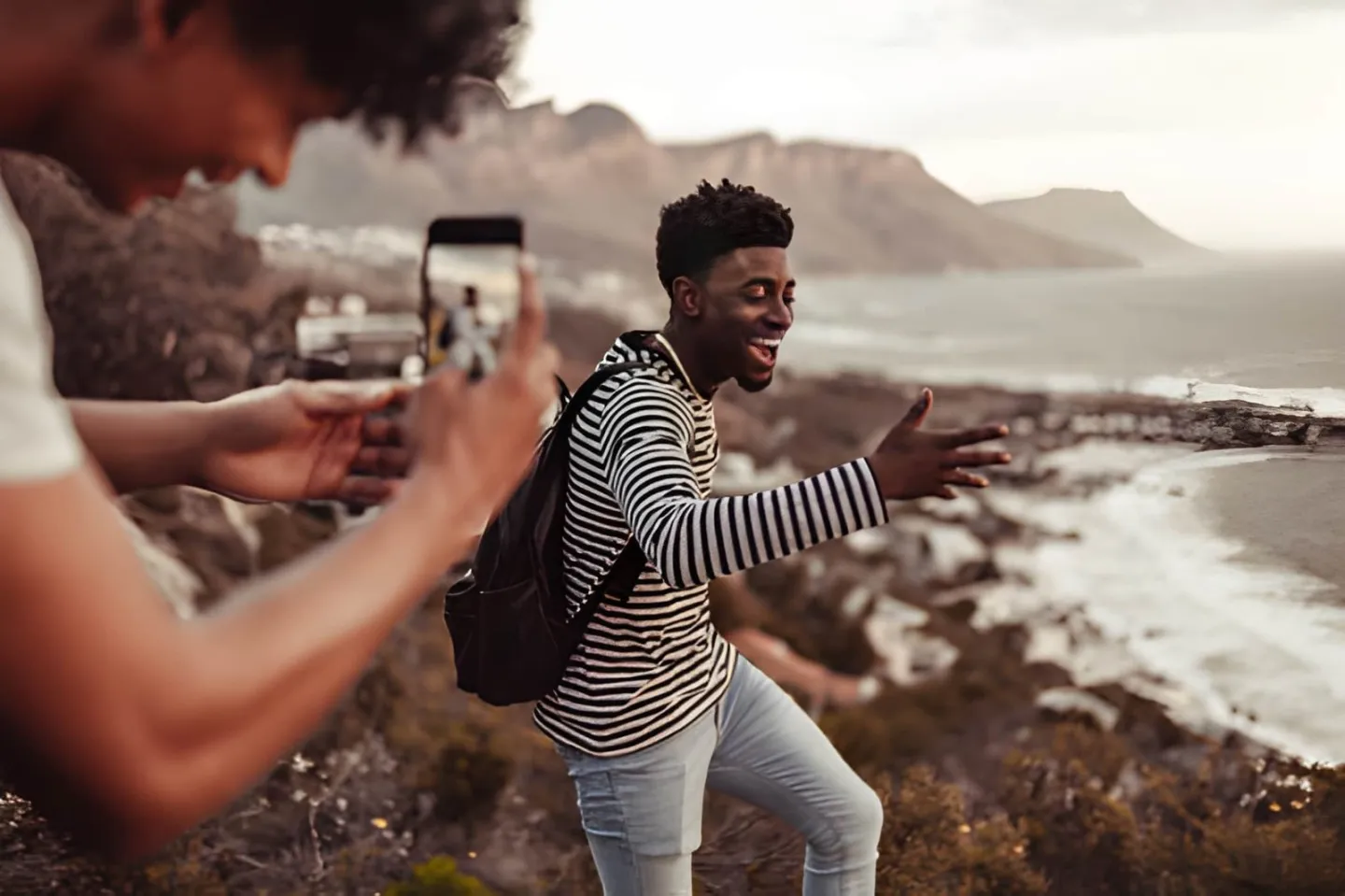 Man filming a vertical video with a smartphone on a coastal trail for TikTok